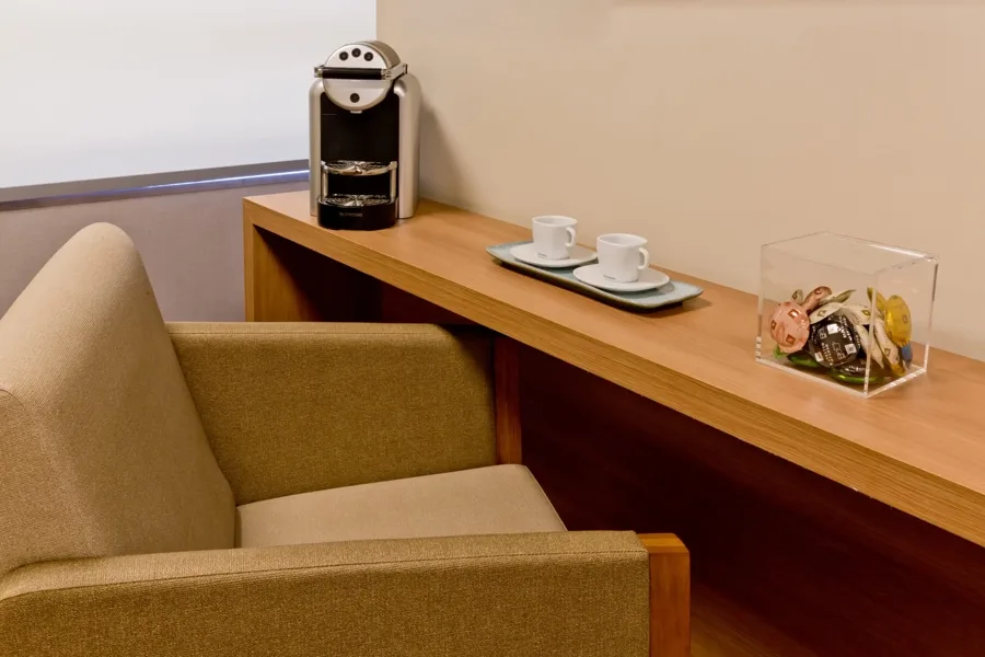 Espaço de espera do hospital com poltrona e estação de café
