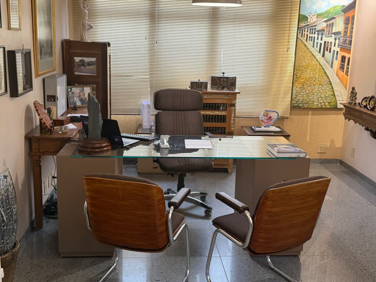 Consultório do Dr. Delzio com mesa de atendimento e quadros na parede