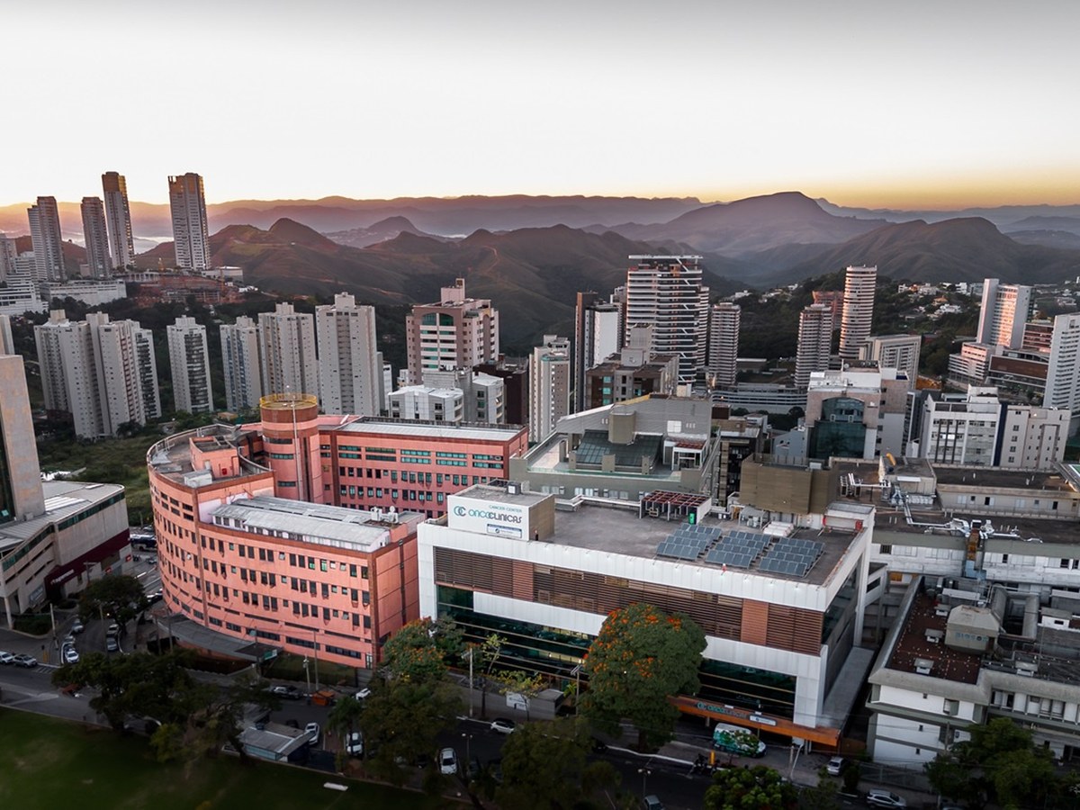 Vista aérea do complexo do Hospital Vila da Serra em Nova Lima ao amanhecer, com o Cancer Center Oncoclínicas ao lado e as montanhas ao fundo