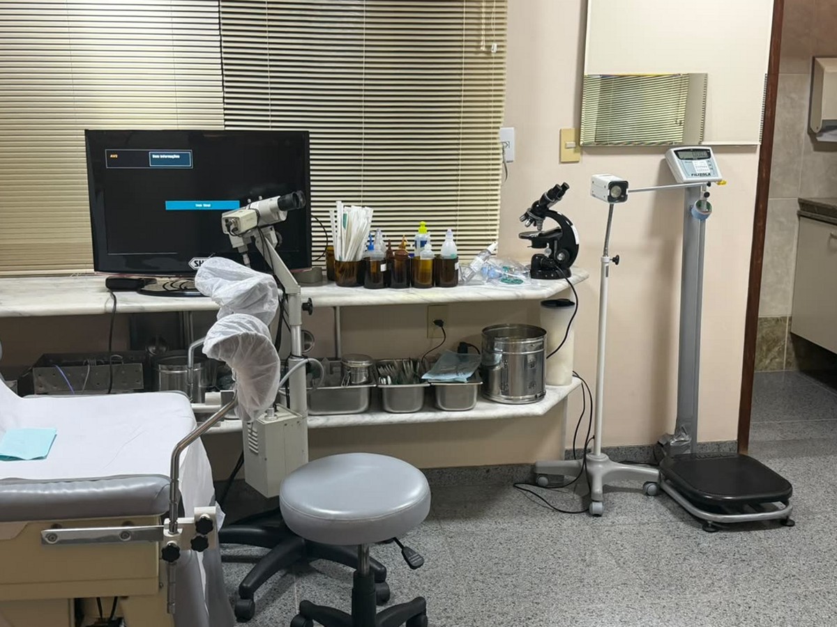 Sala de exames da clínica equipada com colposcópio, microscópio e maca ginecológica